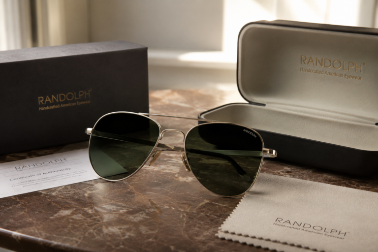 Gafas de sol Randolph originales junto a su estuche, paño de limpieza y certificado de autenticidad en una composición premium.